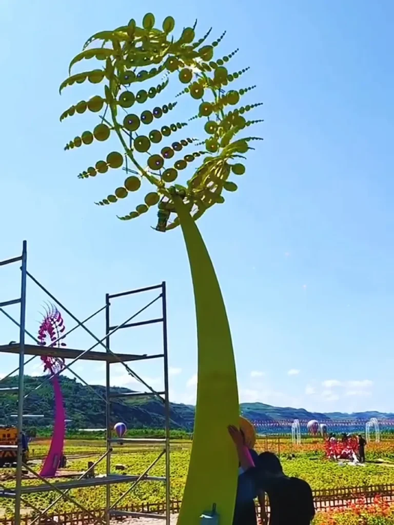 Professional installation of a large kinetic wind sculpture for sale, showing the assembly of the reinforced internal structural skeleton on a curved pole.