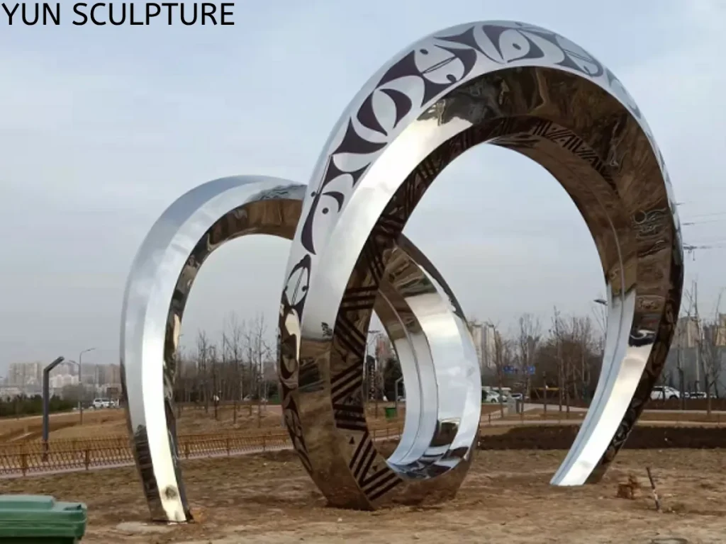 Installation of a large stainless steel ring sculpture on site, showcasing the geometric precision and structural integrity of modern public art sculptures.