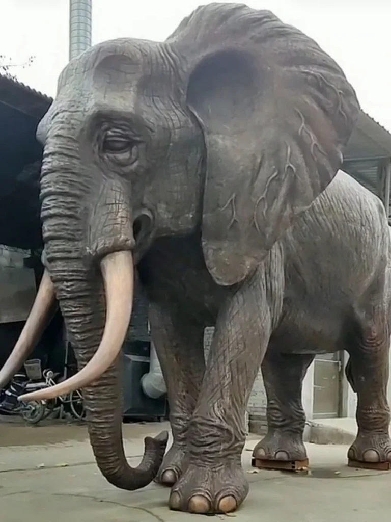 A completed, life-sized bronze elephant statue with highly realistic painted skin texture and patina, standing ready for delivery in a factory yard. This monumental piece is designed as a strong visual anchor for botanical gardens, reflecting pools, or luxury estate landscapes.