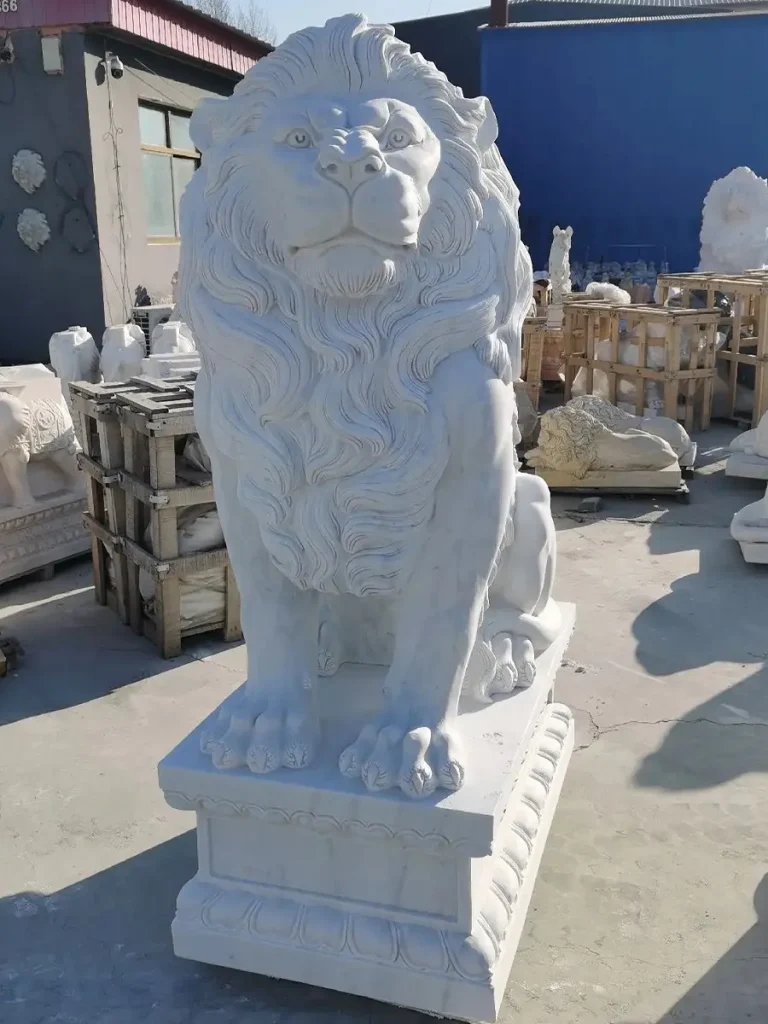 Front-angle view of a large white marble European-style lion statue in a stonemason's yard. Its tall, upright posture and thick, detailed mane provide the substantial visual weight needed to anchor a grand driveway entrance without being overshadowed.