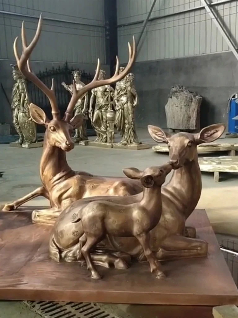 Full view of a magnificent life-size bronze deer family sculpture in a foundry setting. This incredibly durable and deeply detailed artwork not only dictates the lifespan of the piece but perfectly sets a serene, natural atmosphere for any luxury garden or landscape design.