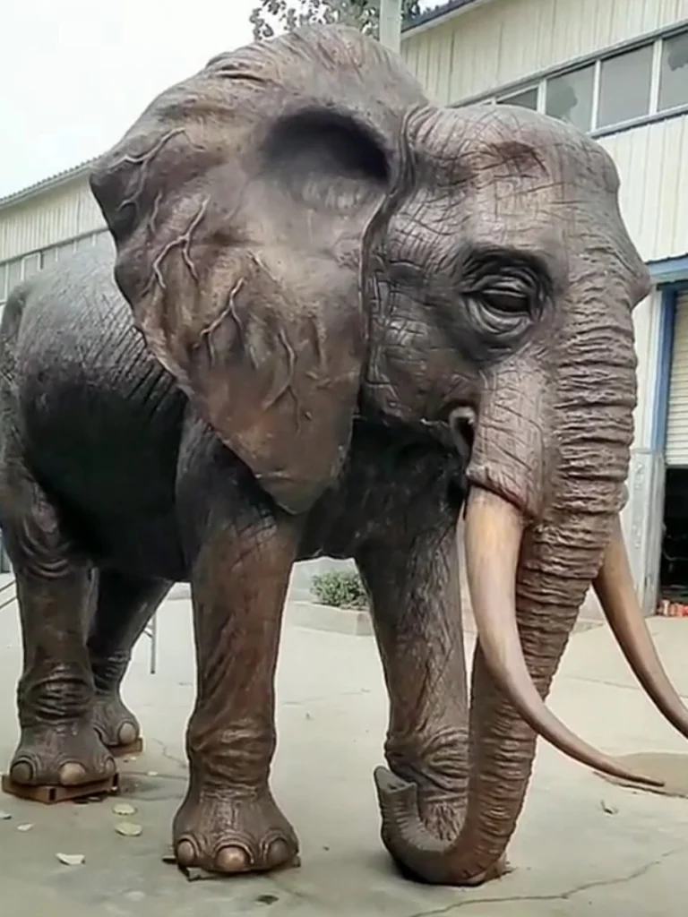A magnificent finished large bronze elephant sculpture featuring incredibly lifelike skin wrinkles and large tusks. Often used in pairs to frame grand entrances, this big elephant statue communicates strength, stability, and calm dignity for high-end resort landscapes and public spaces.