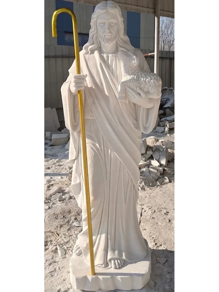 A beautiful marble Jesus statue, handcrafted from high-quality Guangxi white stone, standing in a garden setting, representing the Good Shepherd.