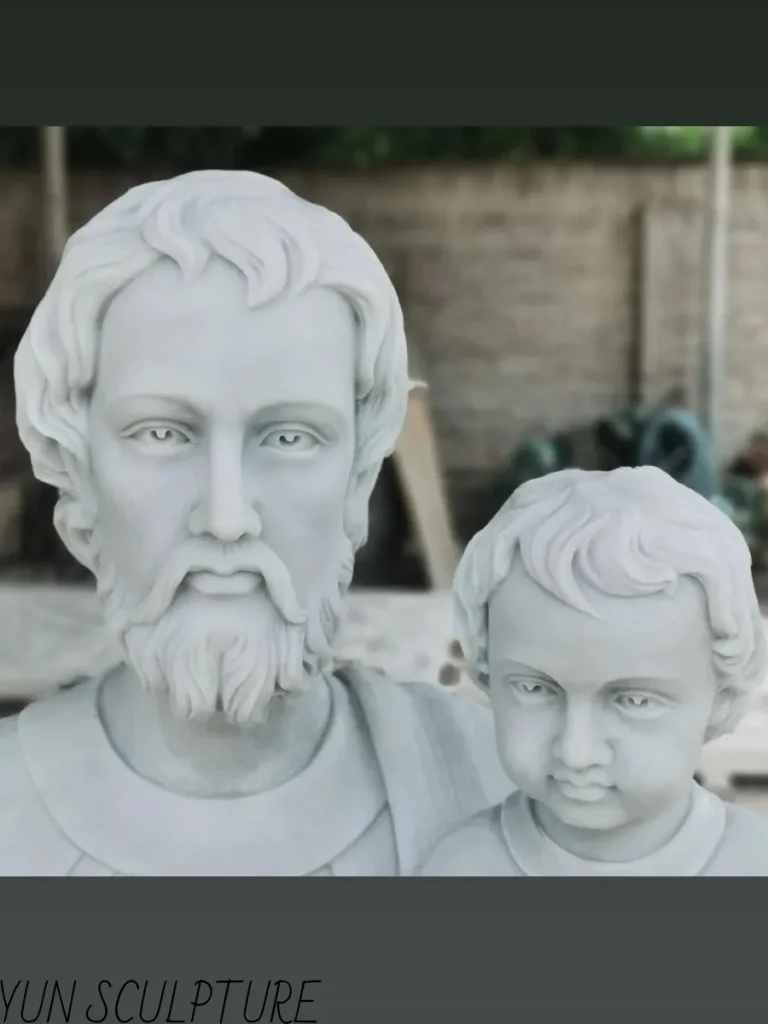 A masterful close-up of a white marble St. Joseph with the Child statue, capturing the incredibly tender facial expressions of both figures. This beautifully hand-carved stone sculpture perfectly represents fatherly protection, love, and the divine guardianship of Saint Joseph over the Infant Jesus.