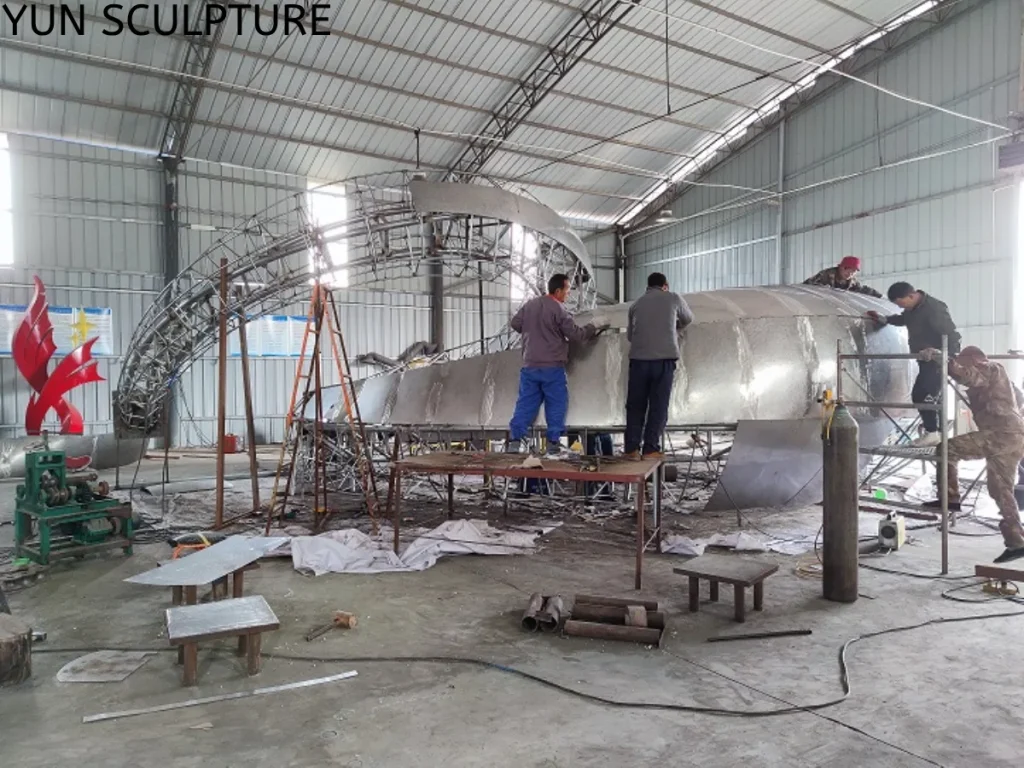 Factory workers assembling the internal steel reinforcement skeleton and radial stiffeners for a large metal moon gate arch to ensure long-term structural integrity.