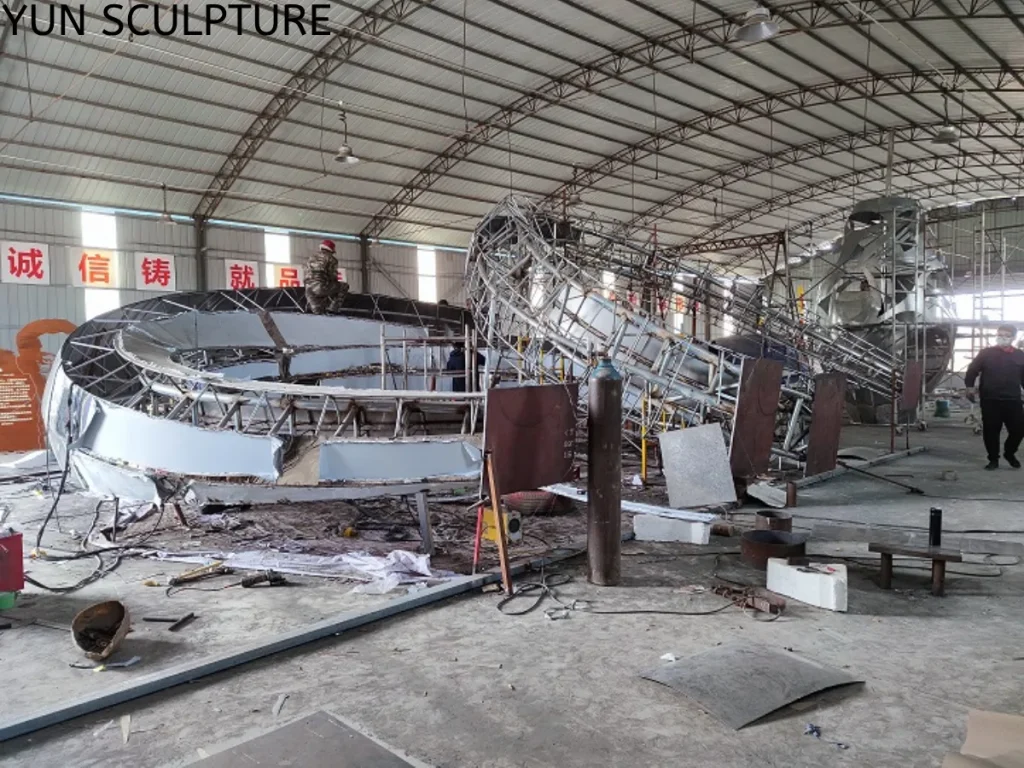 Inside the factory: The internal steel skeleton of a large metal ring sculpture, showing the radial stiffeners and thick wall sections engineered to resist wind load and deformation.