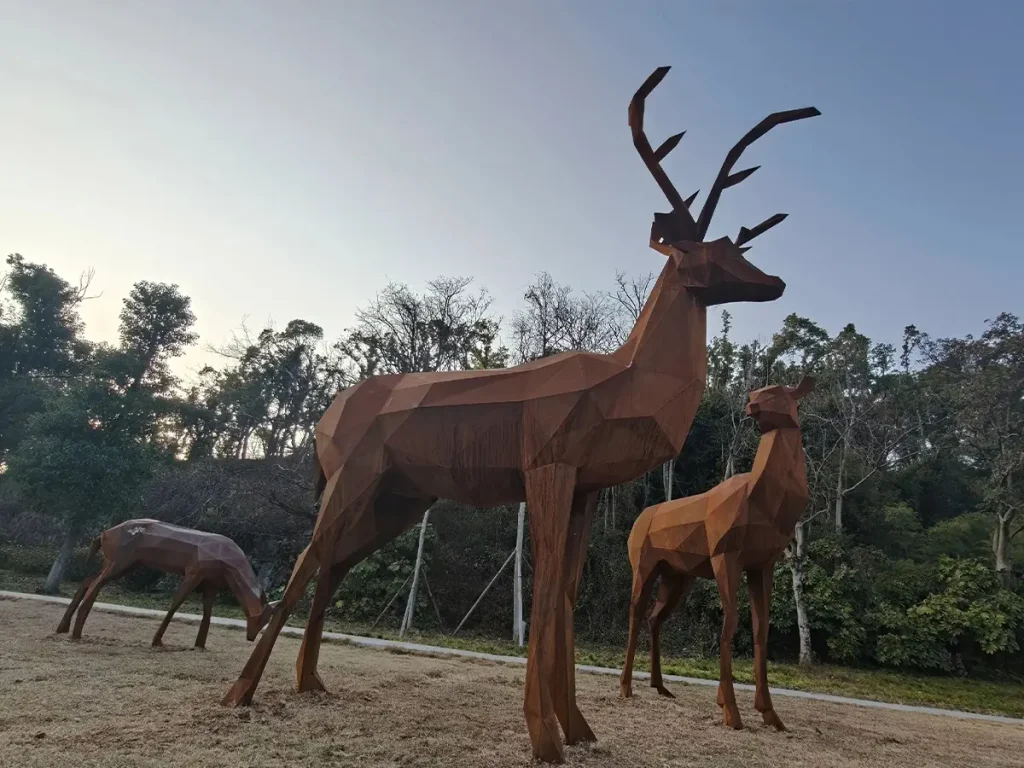 A group of geometric Corten steel deer sculptures at sunset. These sharper, multifaceted metal shapes perfectly complement minimalist architecture and modern courtyards.