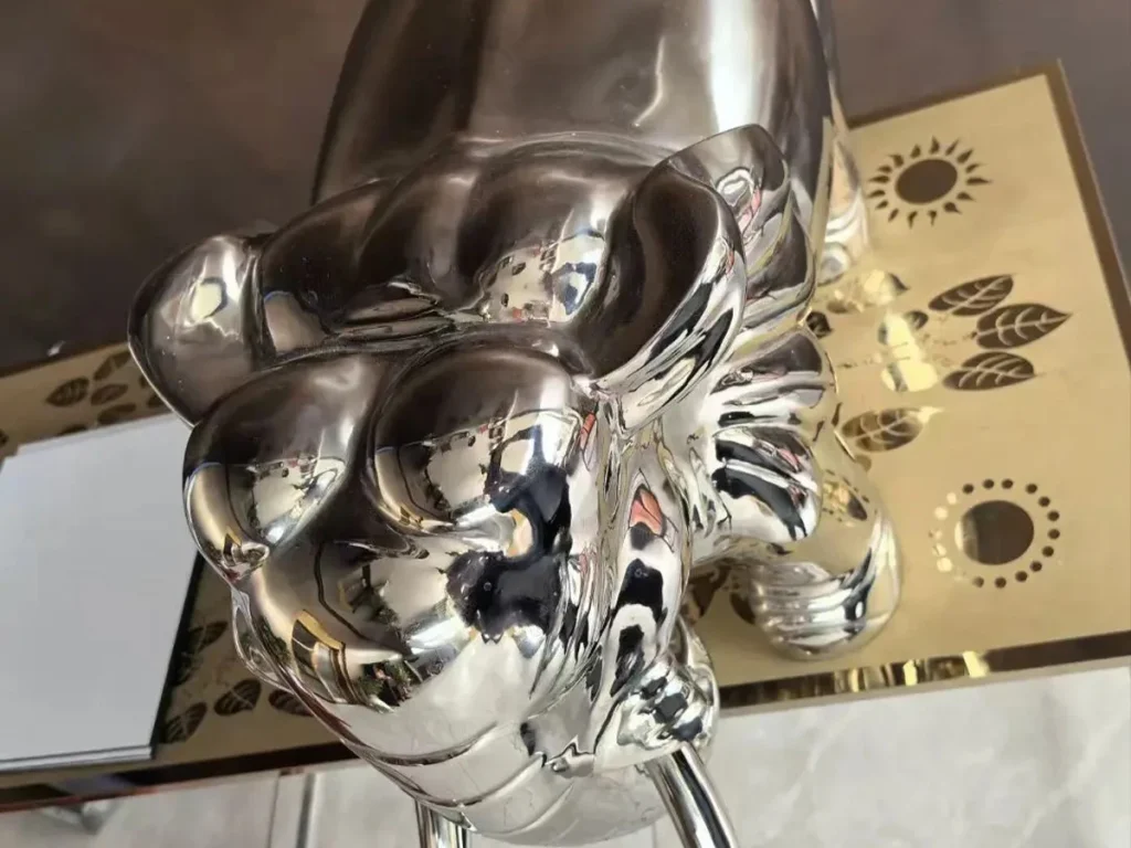 Close-up of a realistic mirror-polished stainless steel elephant head. The gleaming surface highlights the intricate forging technique used to shape the realistic ears and trunk, creating a striking visual presence for luxury hotel gardens and modern residential courtyards.