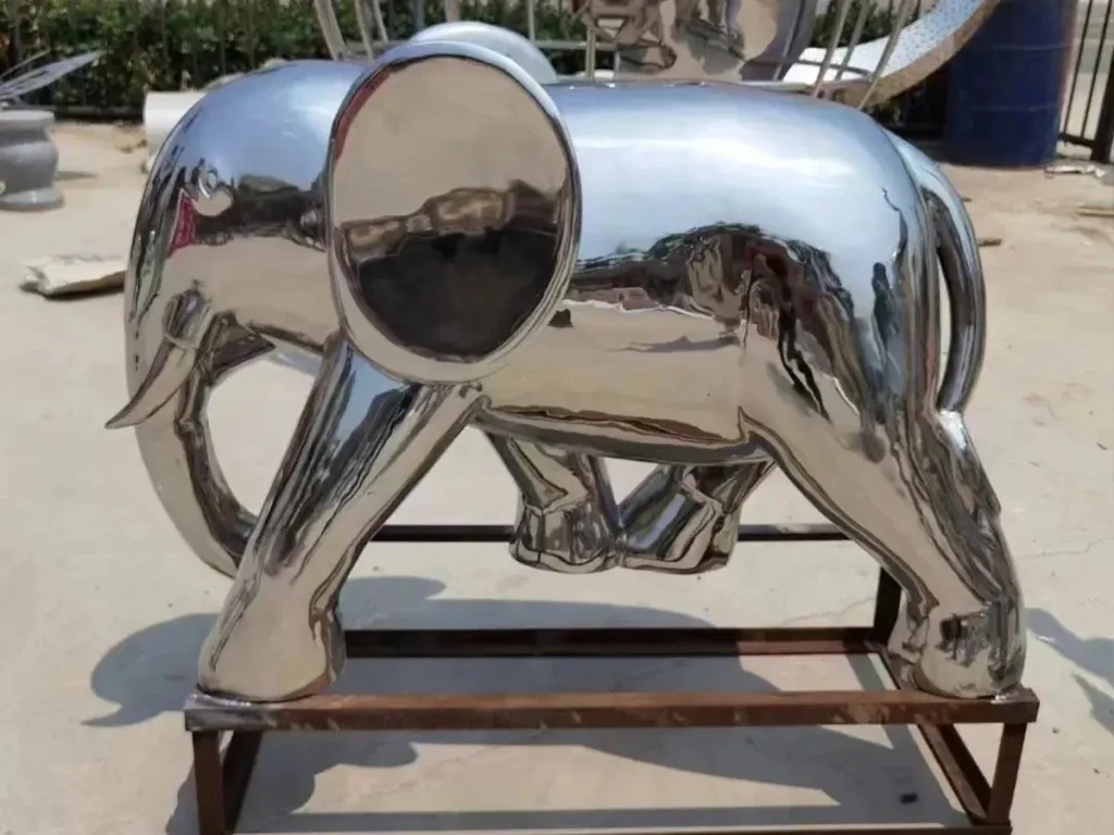 Side view of a stylized, abstract mirror-polished stainless steel elephant. Designed for modern plazas, this smooth, highly reflective 316 stainless steel sculpture acts as a contemporary Feng Shui elephant, interacting dynamically with natural light and surroundings.