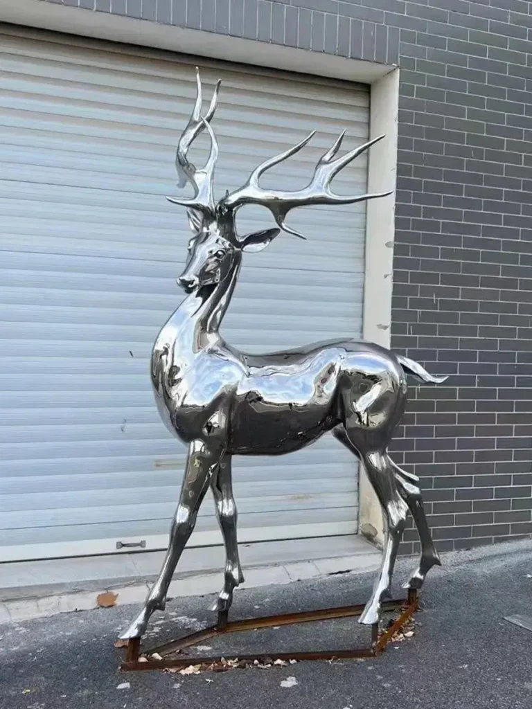 A polished stainless steel metal deer sculpture looking back. The reflective material allows the sculpture to interact with light in dynamic ways, ideal for minimalist landscapes.