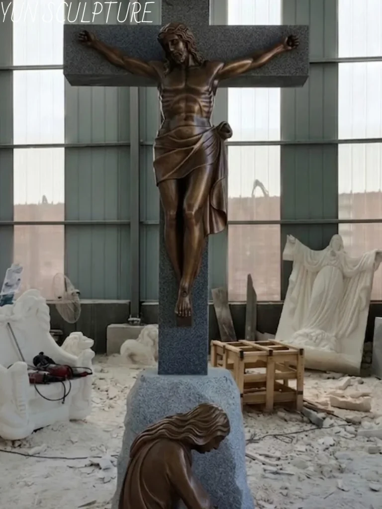 A breathtaking, monumental bronze crucifix and weeping Mary Magdalene statue standing tall in a bustling sculpture foundry. Demonstrating the immense scale of this outdoor memorial installation, the heavy bronze figures and robust granite-textured cross require rigorous foundation engineering drawings and expert on-site assembly sequences provided in our complete installation package.
