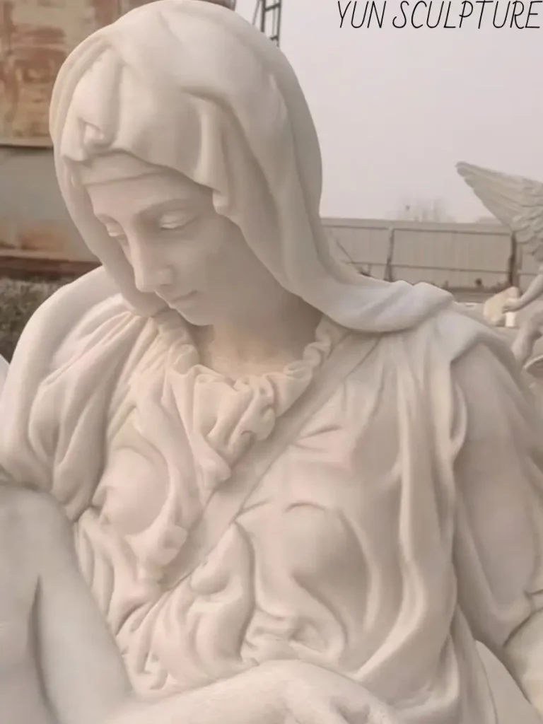 Close-up detail of the Virgin Mary's face from a white marble Pietà sculpture, capturing the delicate expression of compassion and sorrow.