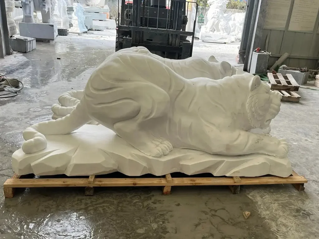 A striking side profile of a masterfully carved white marble tiger statue. The tense, creeping forward movement physically visualizes the flow of protective energy, answering the common question of why placing a powerful tiger statue at home is excellent for property defense.