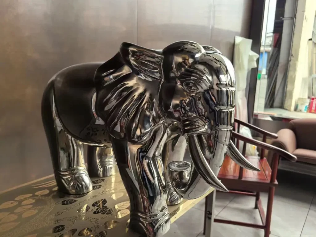 A realistic mirror-polished 316 stainless steel elephant sculpture displayed indoors. Using advanced forging techniques, this modern landscape art piece captures lifelike wrinkles and tusks while reflecting light like a mirror, perfect for contemporary Feng Shui applications.
