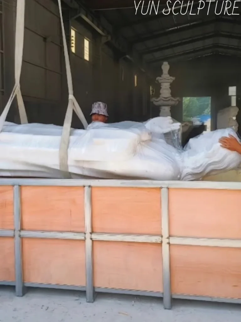 A large white Jesus statue being carefully hoisted by professional equipment for secure packaging and international shipping.