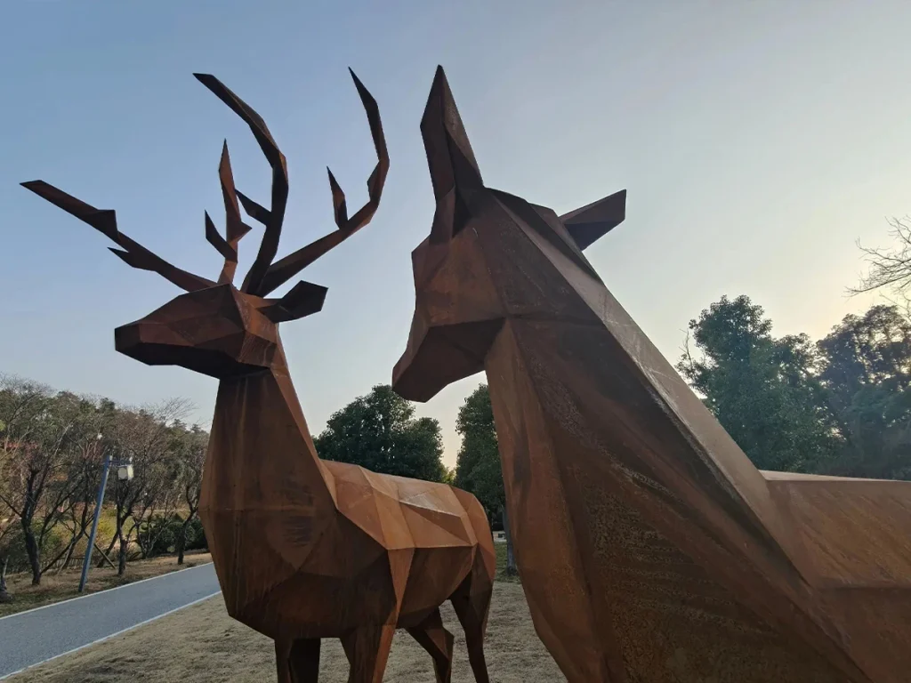 Close-up of a modern metal deer sculpture featuring sharp, geometric lines. The multifaceted design provides a striking visual contrast for contemporary landscape designs.