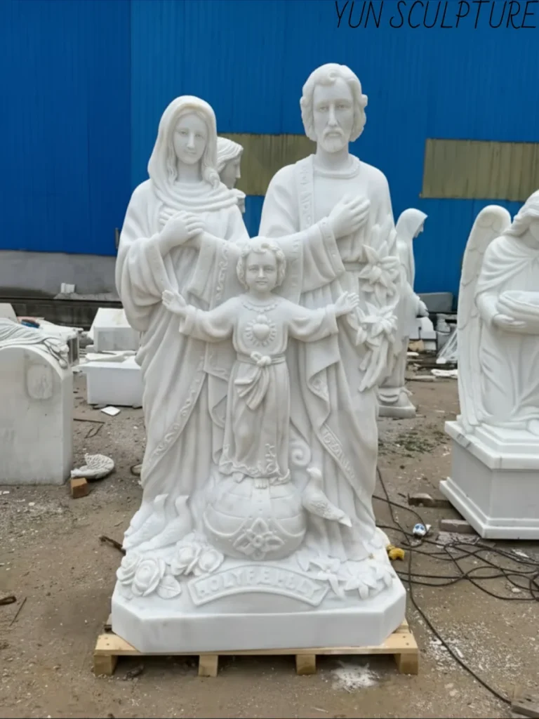 A white marble Holy Family statue carved from a single block of stone, showing the seamless compositional unity and negative space between Jesus, Mary, and Joseph.