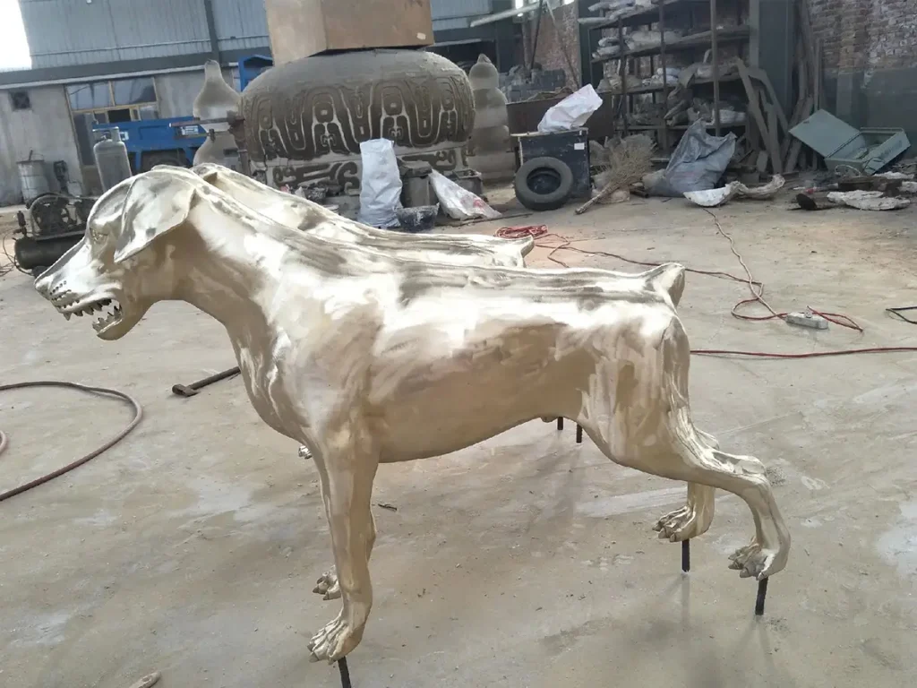 A solid bronze dog statue during the metal casting and polishing process in our foundry, before the final weather-resistant patina is applied.