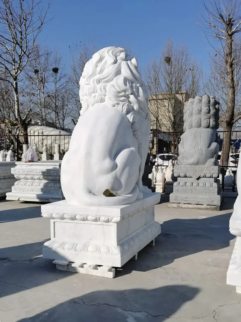 Rear view of a large outdoor white marble lion statue, showcasing its smooth, polished back and curled tail. The solid block of bright white stone emphasizes the extreme visual mass required to serve as a structural design element for grand entrances.