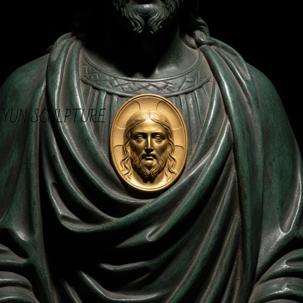 Close-up of a bronze St. Jude statue showing the Christ medallion with a bright gold patina, serving as the theological focal point against the deep statuary brown of the garment.