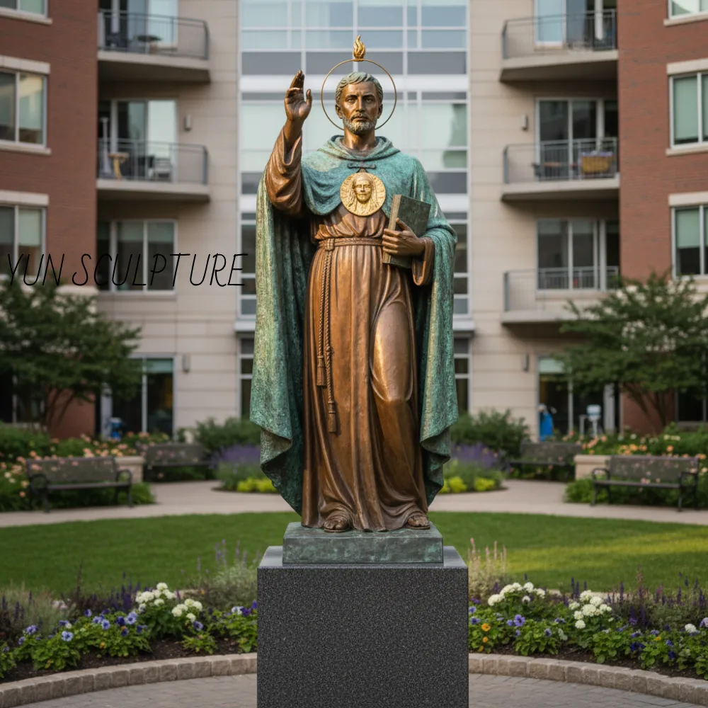 A monumental bronze St. Jude Thaddeus statue with a verde antique patina, featuring the flame of the Holy Spirit and a golden medallion, standing on a reinforced pedestal in a palliative care garden.