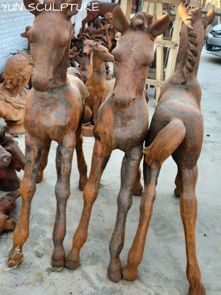 Three weathered iron horse statues standing outdoors, demonstrating the natural oxidation process that highlights the need for a UV-protective sealant clear coat to optimize their life cycle cost.
