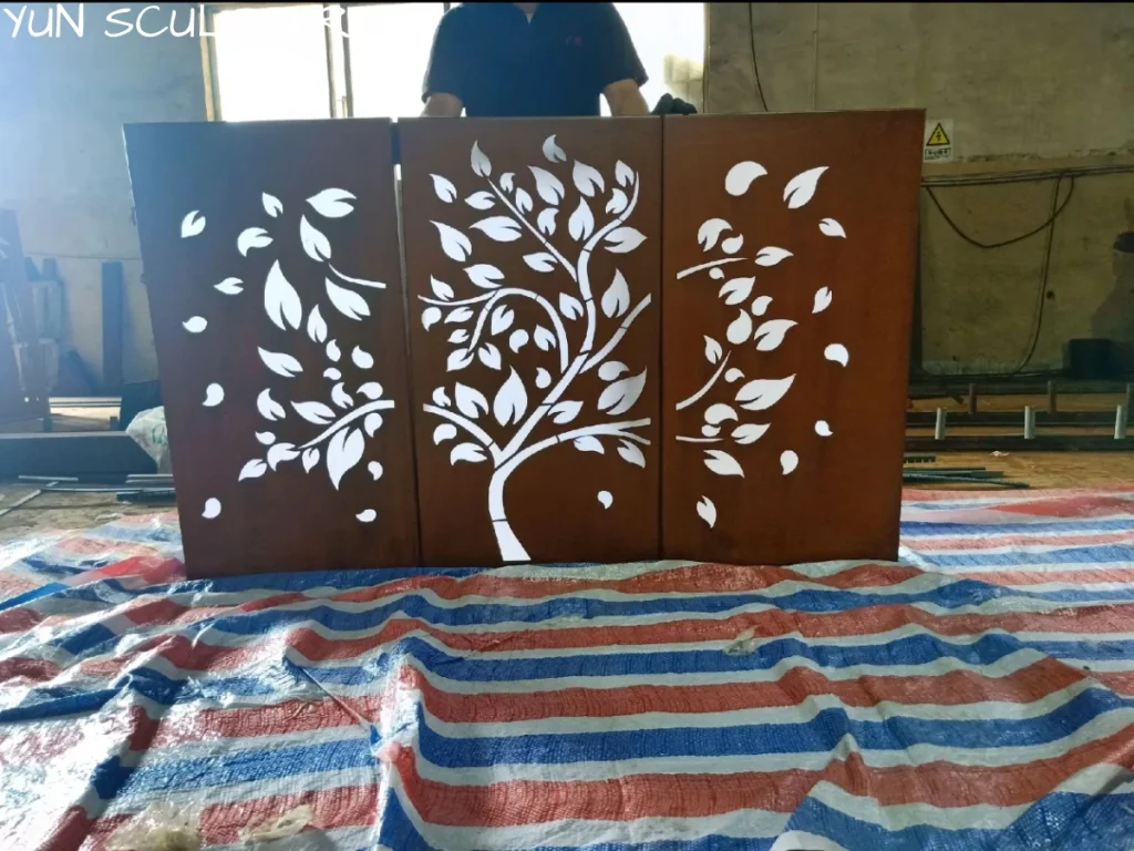 Corten steel art panels with tree and leaf laser cut patterns displayed on fabric