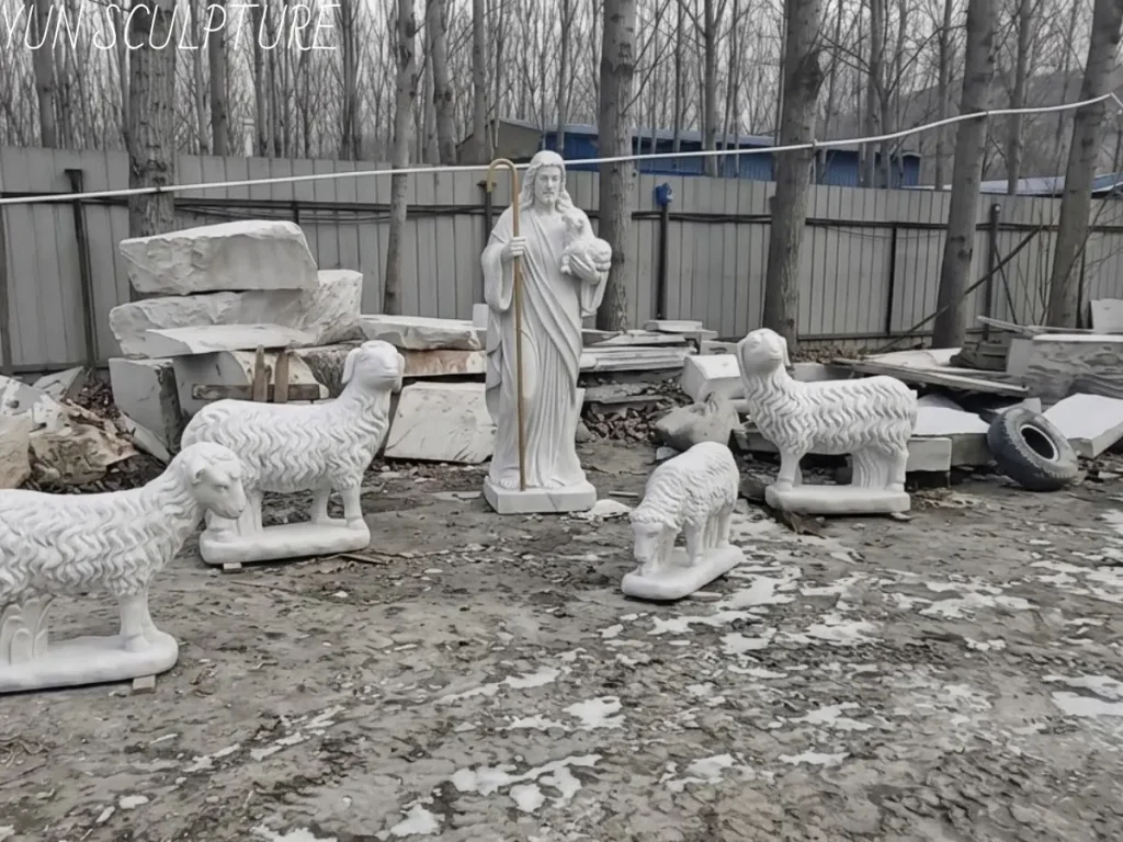 A complete garden sculpture set featuring a tall marble Jesus as the Good Shepherd surrounded by several hand-carved white marble sheep, showcasing a permanent spiritual centerpiece for a private estate garden.