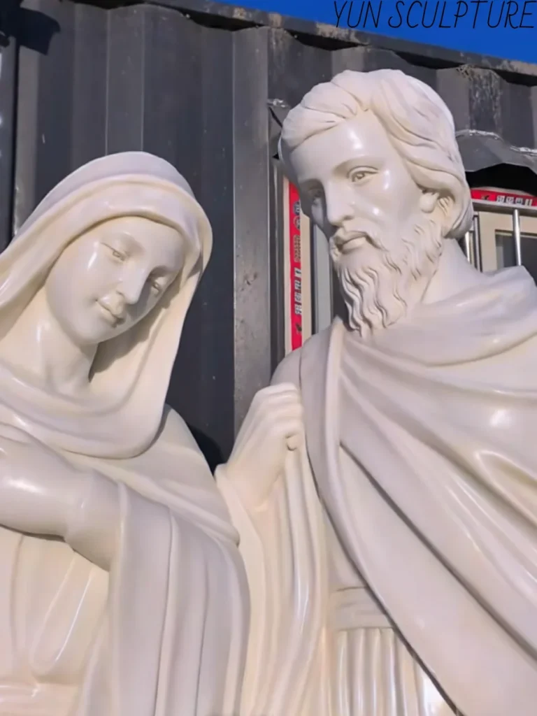 Close-up of the intricately carved faces of Mary and Joseph in a white marble Holy Family sculpture, highlighting the soft, skin-like texture known as morbidezza.
