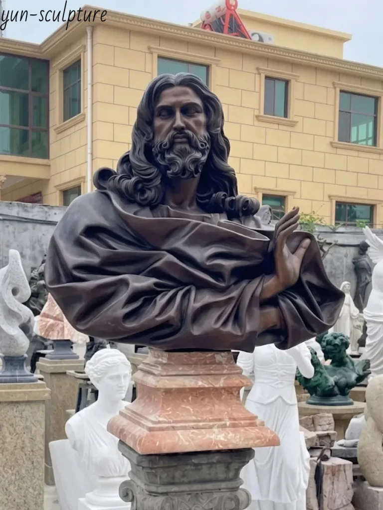 The finished bronze Jesus statue mounted on an elegant marble pedestal outdoors. Featuring a rich, dark metallic sheen, the sculpture beautifully demonstrates how the expert application of patina gives the artwork an immediate sense of age, character, and deep spiritual resonance.