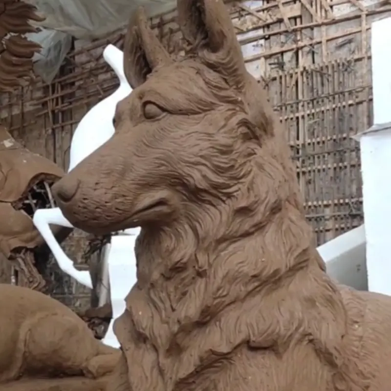 Sculptor hand-shaping clay model of Sheepdog head in foundry workshop
