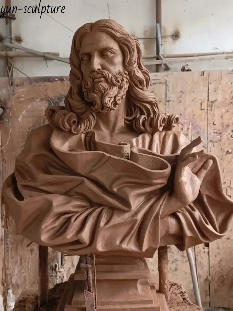 Frontal view of the clay prototype for a bronze Jesus face statue. The meticulous hand-sculpting reveals the subtle curves of the lips, deep eyes, and flowing hair, achieving a lifelike, breath-like presence that static materials like carved stone or wood simply cannot replicate.