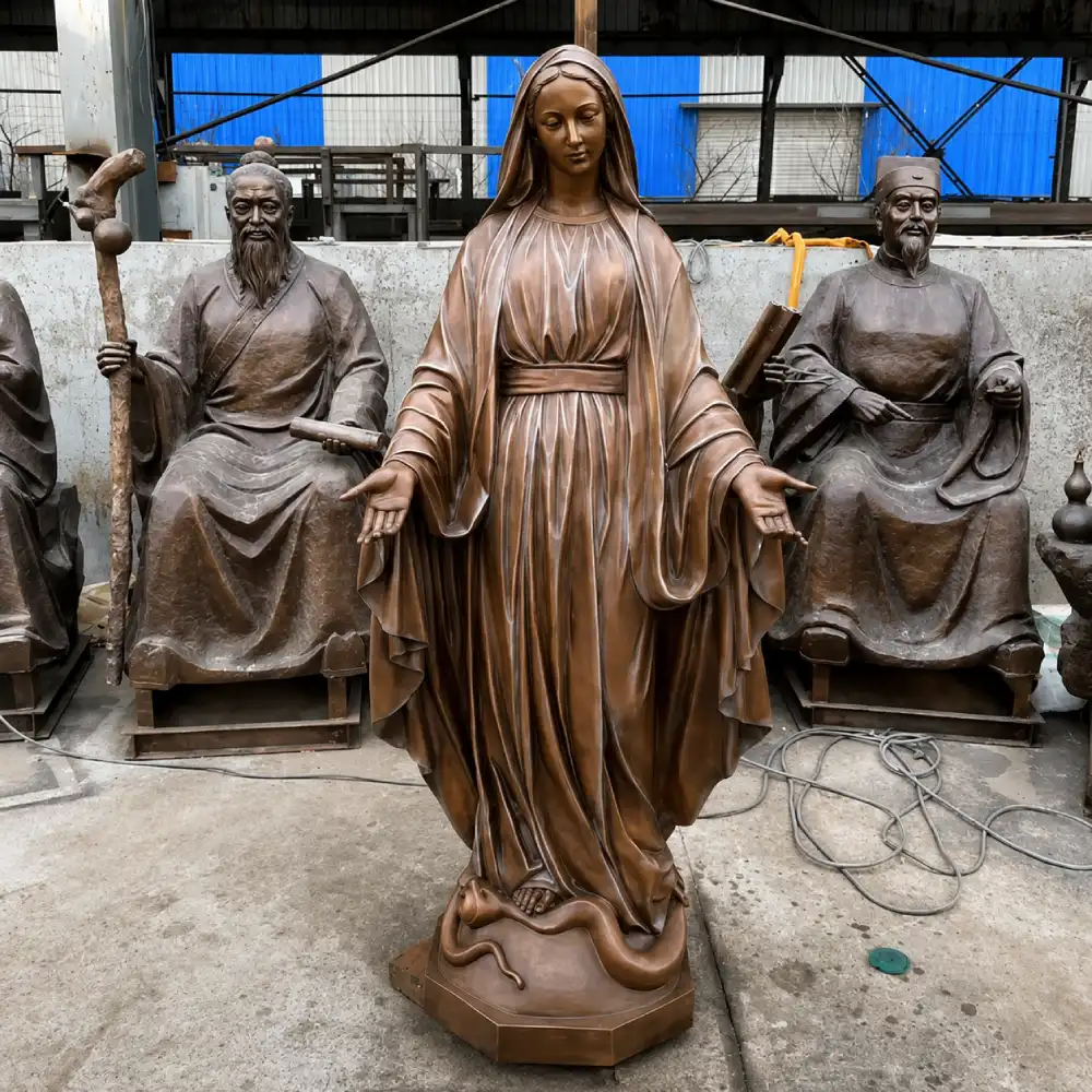 A life-size cast bronze Our Lady of Grace statue in our foundry. Unlike marble or resin, cast bronze handles extreme freeze-thaw cycles and -25°F temperatures without structural damage, developing a beautiful natural patina over decades of outdoor exposure.