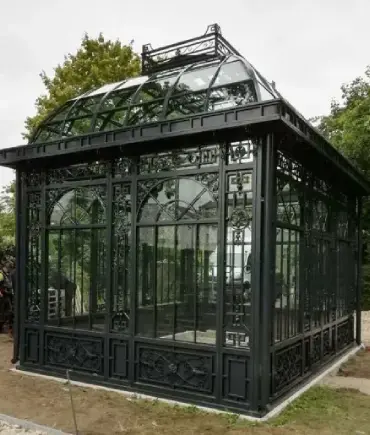 Black wrought iron rectangular greenhouse with tempered glass panels and pitched roof