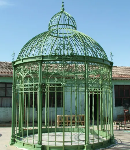 Green Victorian wrought iron conservatory with ornate domed roof and scrollwork