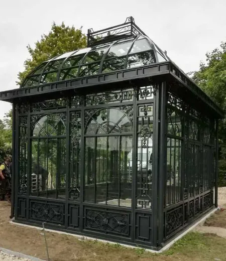 A permanent Victorian-style black wrought iron garden pavilion featuring large glass windows and a tiered roof, designed as a lasting architectural landmark.