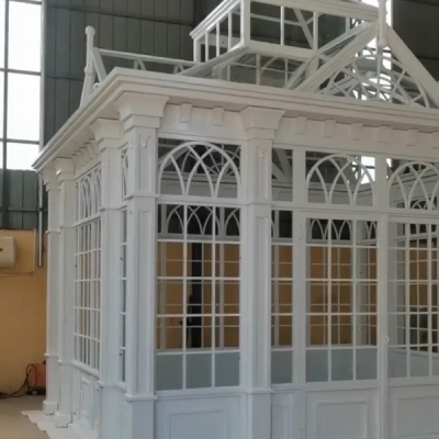 White wrought iron French-style conservatory with arched windows and finials at factory