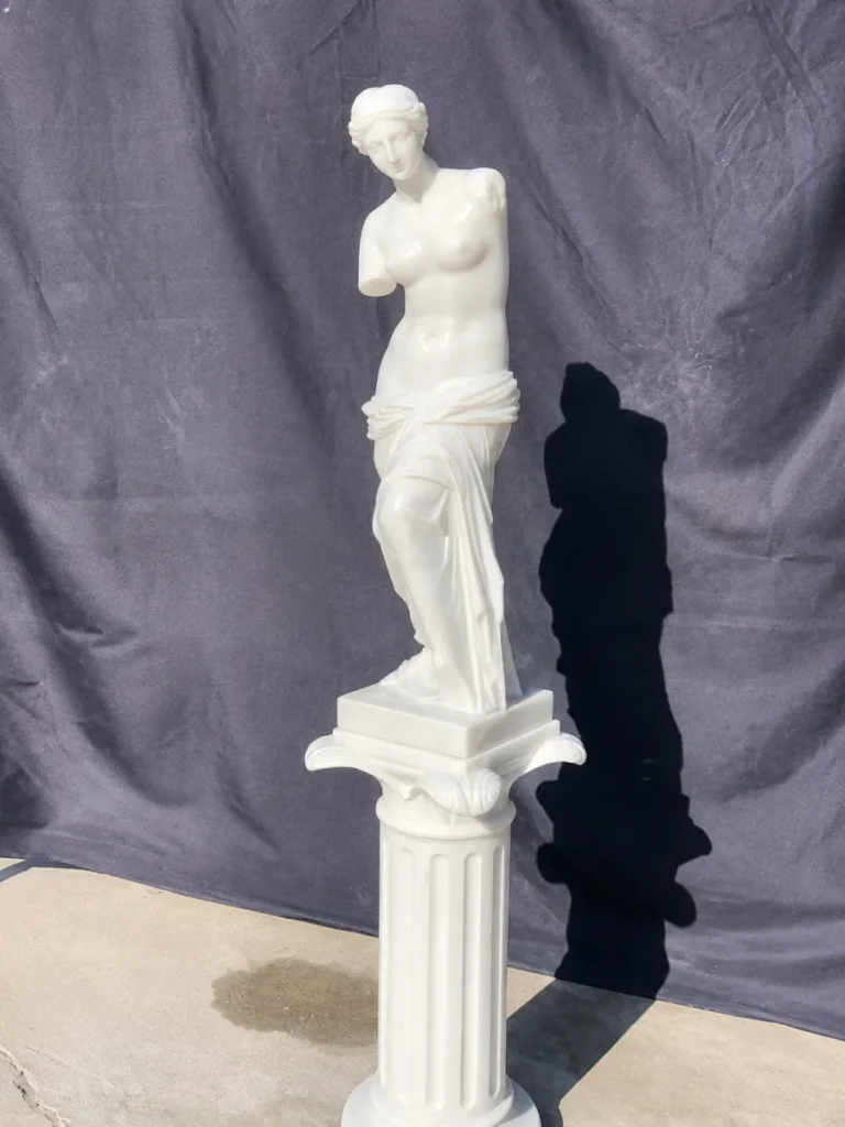 An 80cm scaled-down white marble Venus de Milo statue mounted on a fluted fluted pedestal. This piece demonstrates how the composition and drapery folds simplify at a smaller scale, creating an evocative icon for garden or interior spaces as discussed in our guide.
