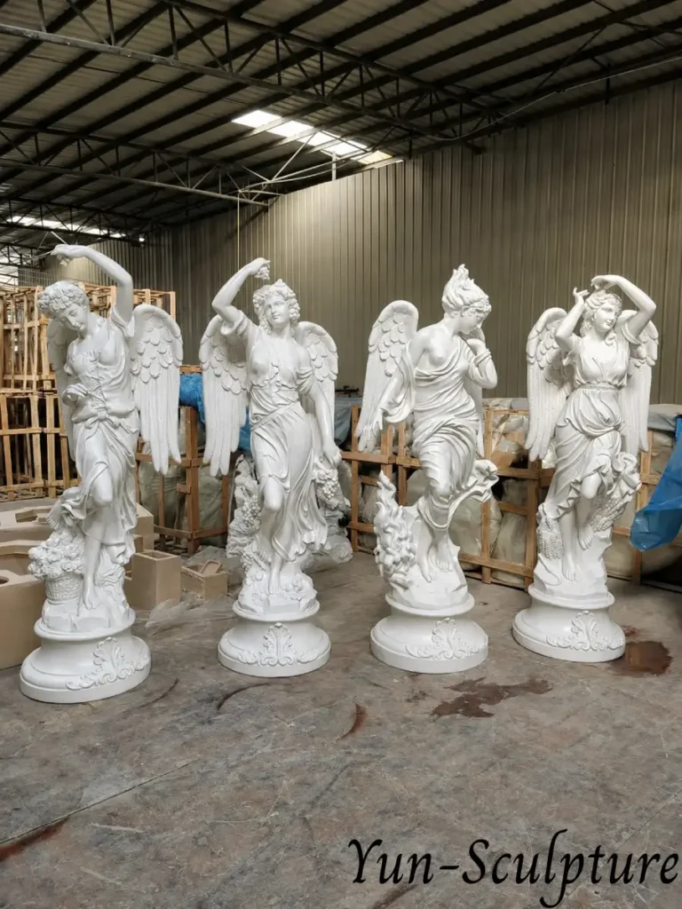 A collection of four life-size winged goddess statues in white stone, demonstrating the three degrees of classical drapery: fully robed for public authority, partially draped for private sanctuaries, and the visually dynamic hybrid style as described in our commission guide.
