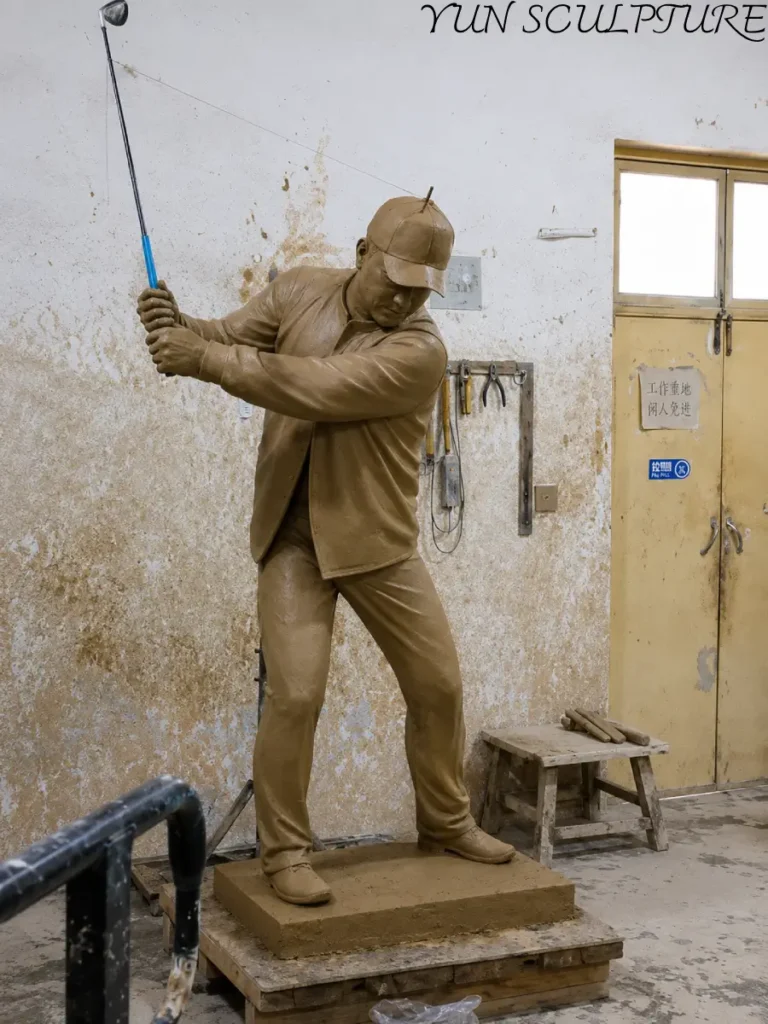 A 1:1 scale clay commission for a vintage-style bronze golfer, showing the detailed textures of the trousers and shirt before the lost-wax casting process begins at Yun Sculpture.