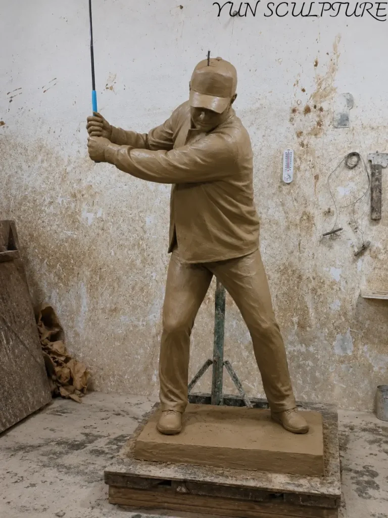 A full-scale clay model of a vintage-style golfer statue, meticulously sculpted with period attire such as knickerbockers and a cloth cap to evoke the pre-modern era of the game.