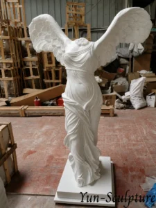 A life-size white marble replica of the Winged Victory of Samothrace (Nike) in our workshop. Given the structural complexity and leverage stress of the feathered wings, this marble version is ideal for sheltered interior display or covered garden niches as described in our guide.