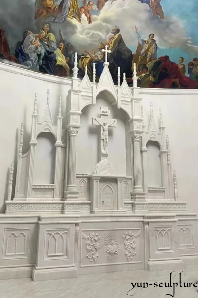 A majestic hand-carved white marble Gothic reredos and altar set in a cathedral, featuring an intricate crucifix and pointed arch architectural details. This project exemplifies our expertise in creating sacred liturgical spaces for modern and historic church renovations.