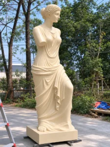 A large-scale, hand-carved replica of the Venus de Milo in natural beige marble, standing in a garden setting. This sculpture faithfully recreates the Hellenistic technique and intricate drapery described in historical records, reflecting the unknown master's refinement of the Praxitelean tradition.