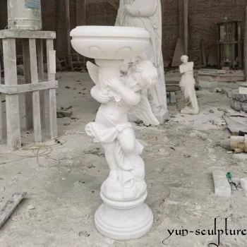 A hand-carved natural white marble baptismal font featuring an angel holding a holy water basin. As a sacred vessel for church interiors, this elegant stone design provides a divine presence for baptisteries and entrance naves, matching our expert church interior design standards.