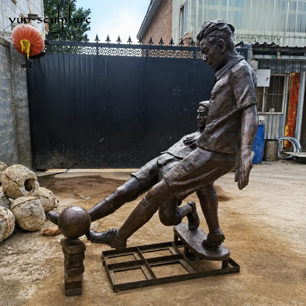 Rear view of a bespoke bronze soccer duel statue at the foundry. This 1:1 scale permanent outdoor monument features precise uniform textures and athletic extension, capturing a specific "celebrating moment" or game action as part of an institutional landmark project.