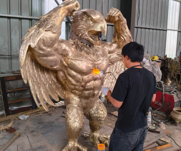 Craftsman polishing and refining the surface of the bronze bluebird sculpture before patina application.