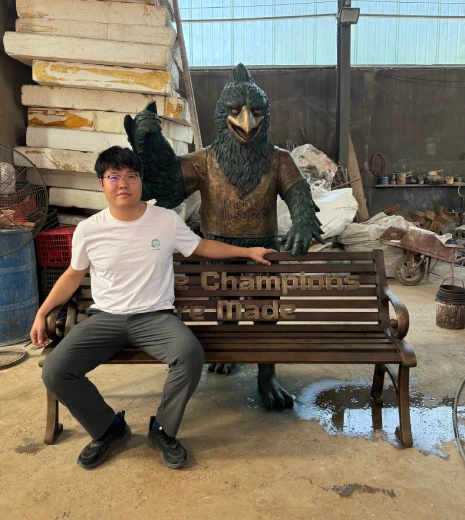Donghui Zhang, Owner of Yun Sculpture, with the finished custom bronze bluebird sculpture and personalized bench before shipment to Arkansas.