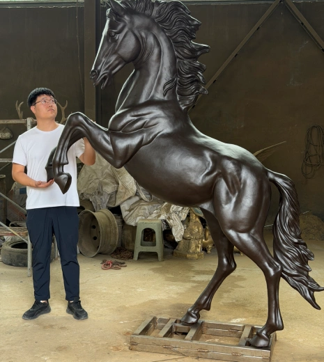 Donghui Zhang, Owner of Yun Sculpture, standing beside the finished custom bronze rearing horse sculpture made for a client in Kuwait.