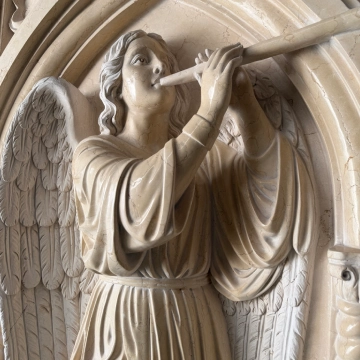 High relief marble angel sculpture with deeply carved wings and detailed stonework
